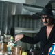 Frank Zappa stirring ingredients in a kitchen, wearing sunglasses and black witch hat
